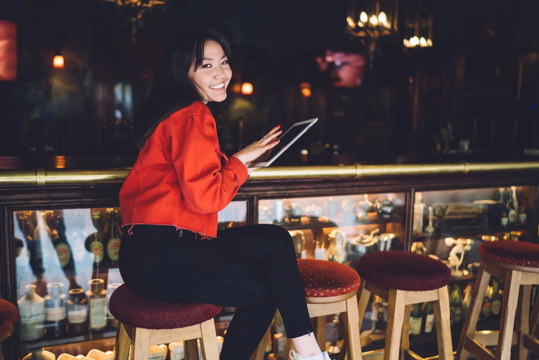 e0b43df7-021e-45f2-84c1-da447b7b9841-1 A woman sitting on top of stools holding an ipad.